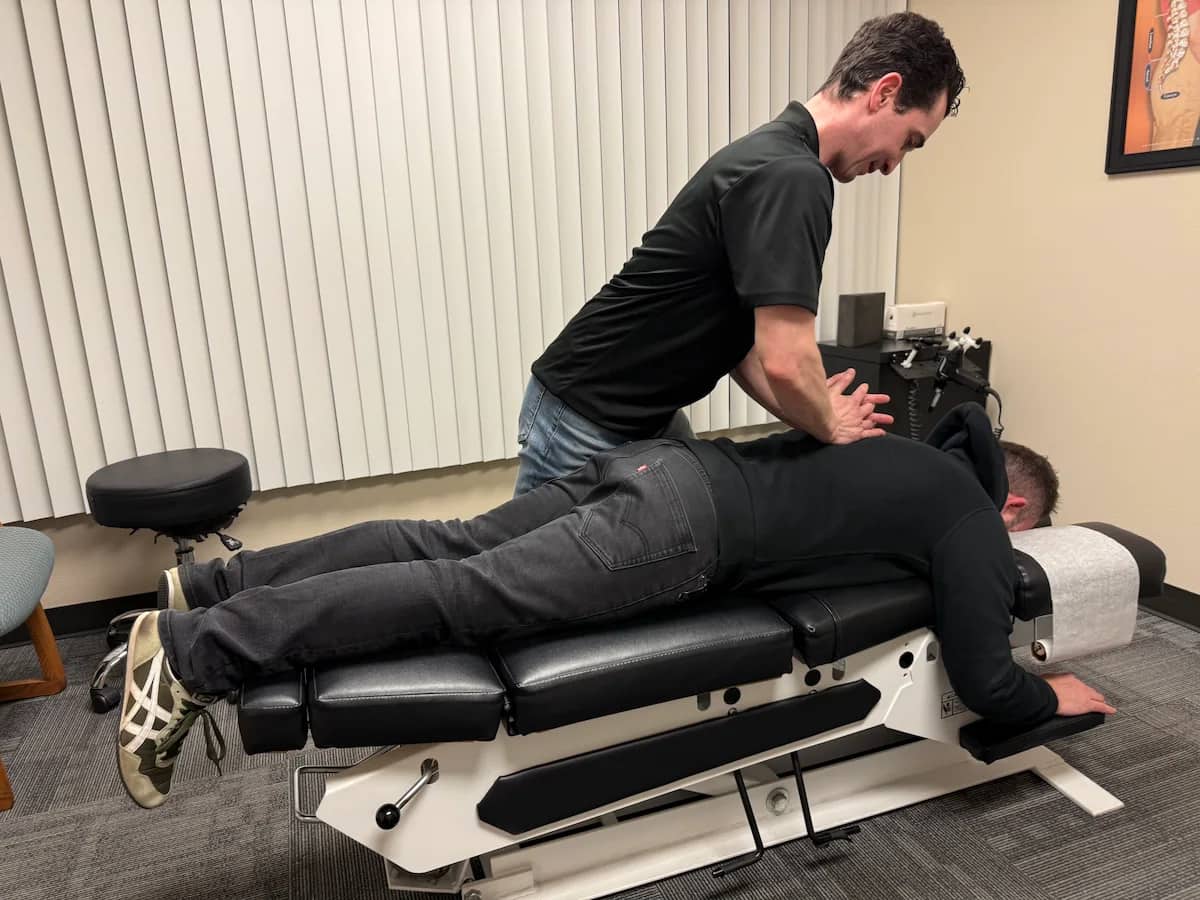 Chiropractor performing thoracic adjustment