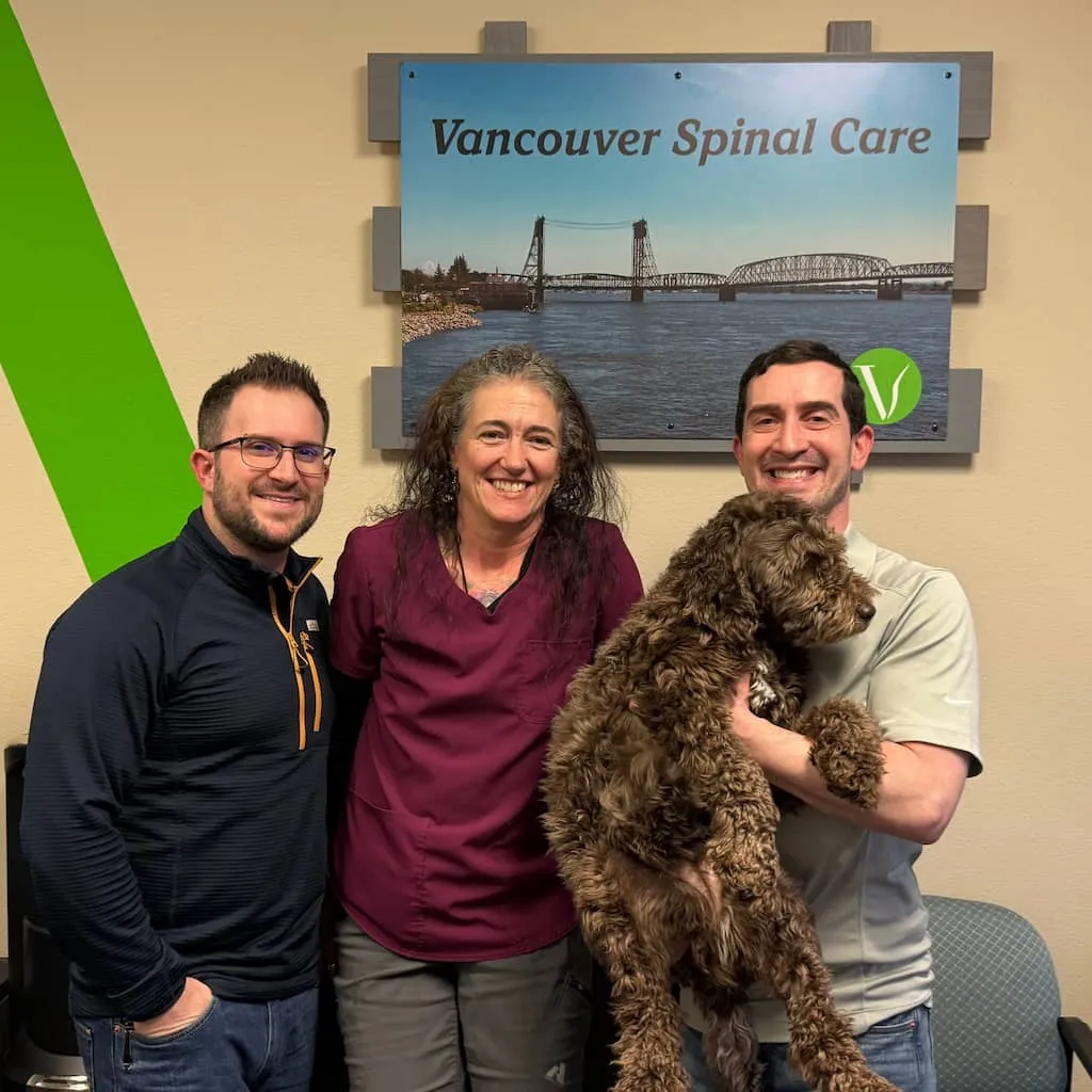 Dr. Scott Freeman and Vancouver Spinal Care team smiling with patient dog Mia in the clinic