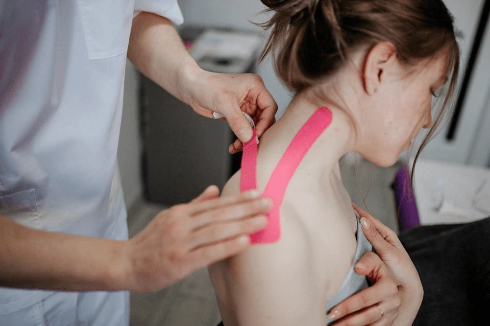 chiropractor applying kinesiology tape on woman neck