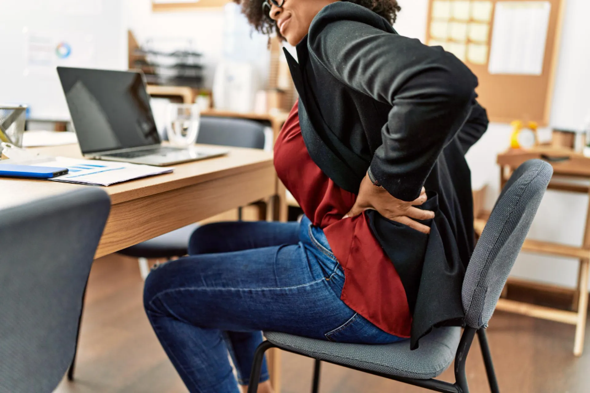 Office worker holding her back in pain from working