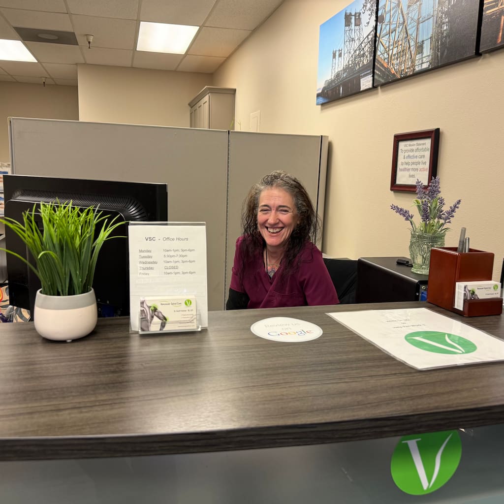 Laura patient advocate smiling at the front desk of Vancouver Spinal Care clinic